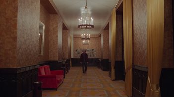 Movie still from “The Shining” (1980), directed by Stanley Kubrick – A man is walking down the hall way of a hotel; Wide shot, Low angle