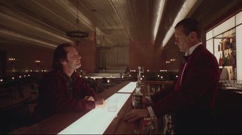 Movie still from “The Shining” (1980), directed by Stanley Kubrick – Two men sitting at a bar talking to each other; Medium shot, Low angle