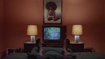 Movie still from “The Shining” (1980), directed by Stanley Kubrick – A person laying in a bed watching television; Wide shot, High angle