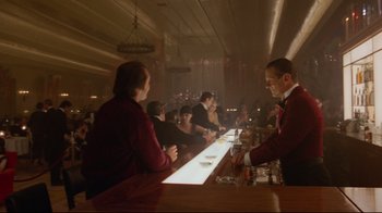 Movie still from “The Shining” (1980), directed by Stanley Kubrick – A group of people sitting at a bar; Wide shot, Low angle