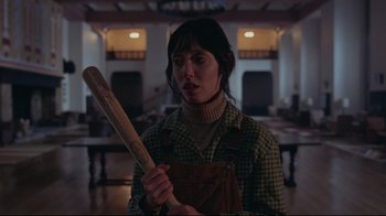 Movie still from “The Shining” (1980), directed by Stanley Kubrick – A woman holding a baseball bat in a room; Medium shot, Low angle
