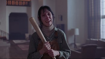 Movie still from “The Shining” (1980), directed by Stanley Kubrick – A woman holding a baseball bat in a room; Medium shot, High angle