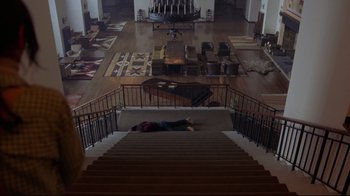Movie still from “The Shining” (1980), directed by Stanley Kubrick – A person laying on the stairs of a house; Extreme Wide shot, Overhead angle