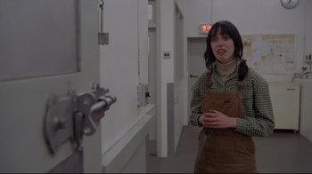 Movie still from “The Shining” (1980), directed by Stanley Kubrick – A woman standing in front of an open door; Medium shot, Over the shoulder angle