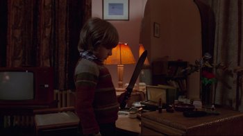 Movie still from “The Shining” (1980), directed by Stanley Kubrick – A young boy is looking at a mirror in a living room; Medium shot, Over the shoulder angle