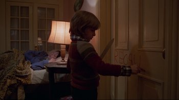 Movie still from “The Shining” (1980), directed by Stanley Kubrick – A young boy holding a large knife in a room; Medium shot, Over the shoulder angle