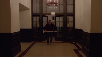 Movie still from “The Shining” (1980), directed by Stanley Kubrick – A woman sitting on the ground in front of a door way; Wide shot, Low angle