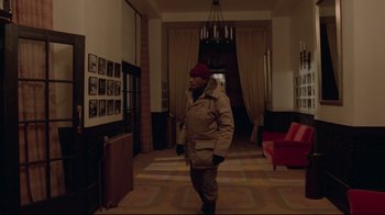 Movie still from “The Shining” (1980), directed by Stanley Kubrick – A man walking in a hallway wearing a coat and hat; Wide shot, High angle