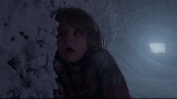 Movie still from “The Shining” (1980), directed by Stanley Kubrick – A young child looking at the camera in the dark; Medium shot, Low angle