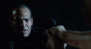 Movie still from “The Terminator” (1984), directed by James Cameron – A man holding a gun in front of a person; Close Up shot, Over the shoulder angle