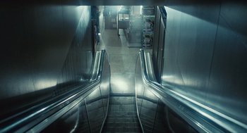Movie still from “The Terminator” (1984), directed by James Cameron – The escalator is going down the steep slope of the stairs; Extreme Wide shot, Overhead angle