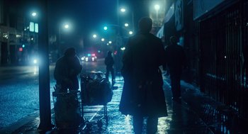 Movie still from “The Terminator” (1984), directed by James Cameron – A group of people walking down a street at night; Wide shot, Over the shoulder angle