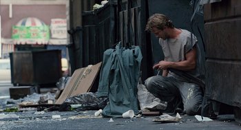 Movie still from “The Terminator” (1984), directed by James Cameron – A man kneeling down next to a bag of trash; Wide shot, Low angle