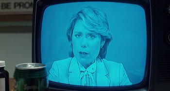 Movie still from “The Terminator” (1984), directed by James Cameron – A television screen showing a woman in a white suit; Close Up shot, Over the shoulder angle