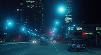 Movie still from “The Terminator” (1984), directed by James Cameron – Cars driving down a street at night in a city; Extreme Wide shot, High angle