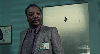 Movie still from “The Terminator” (1984), directed by James Cameron – A man in a suit standing in front of an elevator; Close Up shot, Low angle