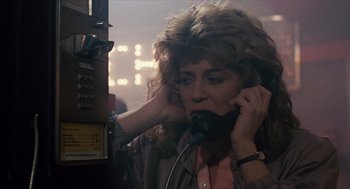 Movie still from “The Terminator” (1984), directed by James Cameron – A woman is talking on a phone in a room with lights; Close Up shot, Low angle