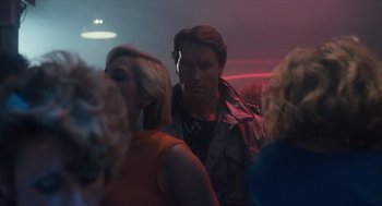 Movie still from “The Terminator” (1984), directed by James Cameron – A group of people standing around in a room at night; Medium shot, Over the shoulder angle