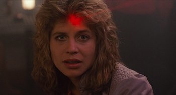 Movie still from “The Terminator” (1984), directed by James Cameron – A person with a red light on their forehead; Close Up shot, Over the shoulder angle
