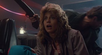 Movie still from “The Terminator” (1984), directed by James Cameron – A woman holding a gun and looking surprised; Close Up shot, Over the shoulder angle