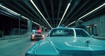 Movie still from “The Terminator” (1984), directed by James Cameron – A police car is driving under a bridge; Wide shot, Low angle