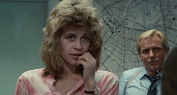 Movie still from “The Terminator” (1984), directed by James Cameron – A woman with a messy hair style is holding a cell phone to her ear; Close Up shot, Over the shoulder angle