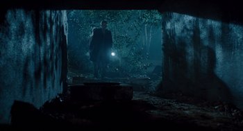 Movie still from “The Terminator” (1984), directed by James Cameron – A man with a flashlight walking through a forest; Wide shot, Low angle