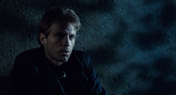 Movie still from “The Terminator” (1984), directed by James Cameron – A man in a black jacket is sitting in a dark room; Close Up shot, Low angle