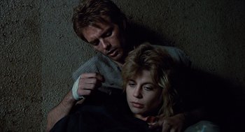 Movie still from “The Terminator” (1984), directed by James Cameron – A man and a woman are sitting on the ground; Close Up shot, Overhead angle