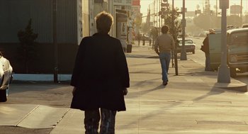 Movie still from “The Terminator” (1984), directed by James Cameron – Two people walking down the sidewalk on a sunny day; Wide shot, Over the shoulder angle