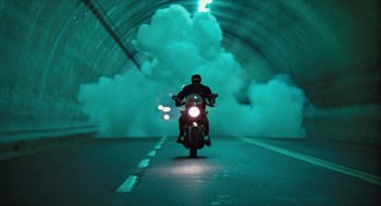 Movie still from “The Terminator” (1984), directed by James Cameron – A man riding a motorcycle through a tunnel; Wide shot, Low angle