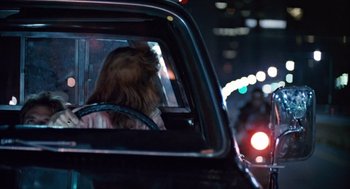 Movie still from “The Terminator” (1984), directed by James Cameron – A woman in the back seat of a car at night; Medium shot, Over the shoulder angle