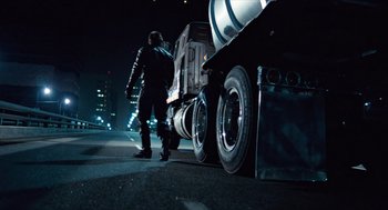 Movie still from “The Terminator” (1984), directed by James Cameron – A man standing next to a truck on the side of the road; Wide shot, Low angle