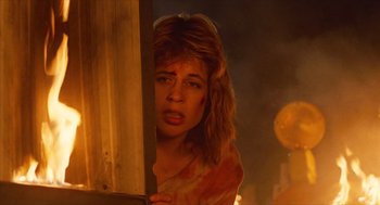 Movie still from “The Terminator” (1984), directed by James Cameron – A young woman is standing in front of a fire; Close Up shot, Low angle