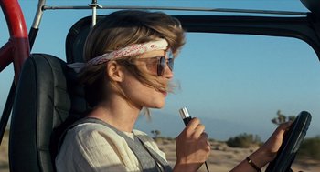 Movie still from “The Terminator” (1984), directed by James Cameron – A woman with a bandana on her head is holding a cell phone; Close Up shot, Over the shoulder angle