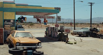 Movie still from “The Terminator” (1984), directed by James Cameron – An empty gas station with a car parked in front of it; Extreme Wide shot, High angle