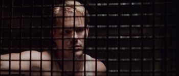 Movie still from “The Thin Red Line” (1998), directed by Terrence Malick – A man sitting in front of a metal fence; Close Up shot, Low angle
