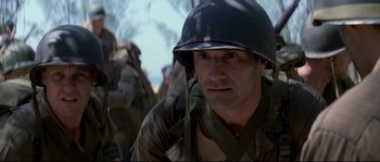 Movie still from “The Thin Red Line” (1998), directed by Terrence Malick – A man wearing a helmet is looking into the distance; Close Up shot, Low angle