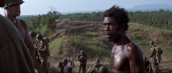 Movie still from “The Thin Red Line” (1998), directed by Terrence Malick – A group of men standing on top of a grass covered hill; Close Up shot, Over the shoulder angle