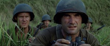Movie still from “The Thin Red Line” (1998), directed by Terrence Malick – A group of men in military uniforms are standing in a field; Close Up shot, Low angle