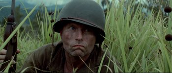 Movie still from “The Thin Red Line” (1998), directed by Terrence Malick – A man wearing a helmet in a field of grass; Close Up shot, Low angle