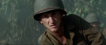 Movie still from “The Thin Red Line” (1998), directed by Terrence Malick – A man wearing a helmet is looking at the camera; Close Up shot, Low angle