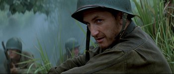Movie still from “The Thin Red Line” (1998), directed by Terrence Malick – A man wearing a helmet and a jacket; Close Up shot, Low angle