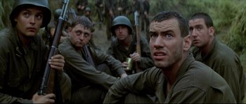 Movie still from “The Thin Red Line” (1998), directed by Terrence Malick – A group of men sitting on top of a dirt field; Close Up shot, Low angle