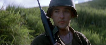 Movie still from “The Thin Red Line” (1998), directed by Terrence Malick – A man holding a rifle in a field; Close Up shot, Low angle