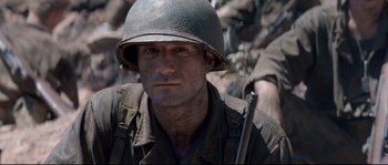 Movie still from “The Thin Red Line” (1998), directed by Terrence Malick – A man with a helmet and a rifle in his hands; Close Up shot, Over the shoulder angle