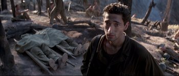 Movie still from “The Thin Red Line” (1998), directed by Terrence Malick – A young man is standing in front of a dead body; Close Up shot, High angle