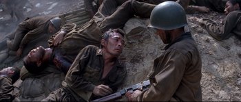 Movie still from “The Thin Red Line” (1998), directed by Terrence Malick – A man in fatigues holding a gun while another man in fatigues looks on; Medium shot, Over the shoulder angle