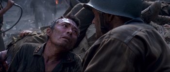 Movie still from “The Thin Red Line” (1998), directed by Terrence Malick – A man in fatigues is talking to another man; Close Up shot, High angle
