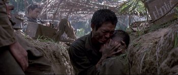 Movie still from “The Thin Red Line” (1998), directed by Terrence Malick – A man holding another man's face in the woods; Close Up shot, Over the shoulder angle